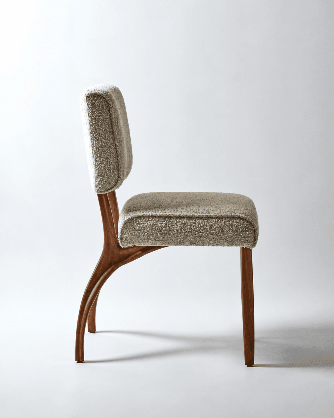 AUREL premium dining chair with a sculptural walnut wooden frame and softly upholstered beige seat and backrest on a light studio background.