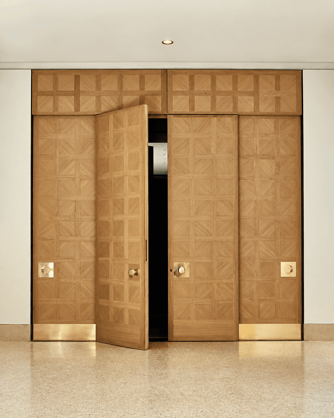 Geometric Timber Double Main Door installed in a minimalist interior, featuring natural wood geometric detailing and metallic base accents.