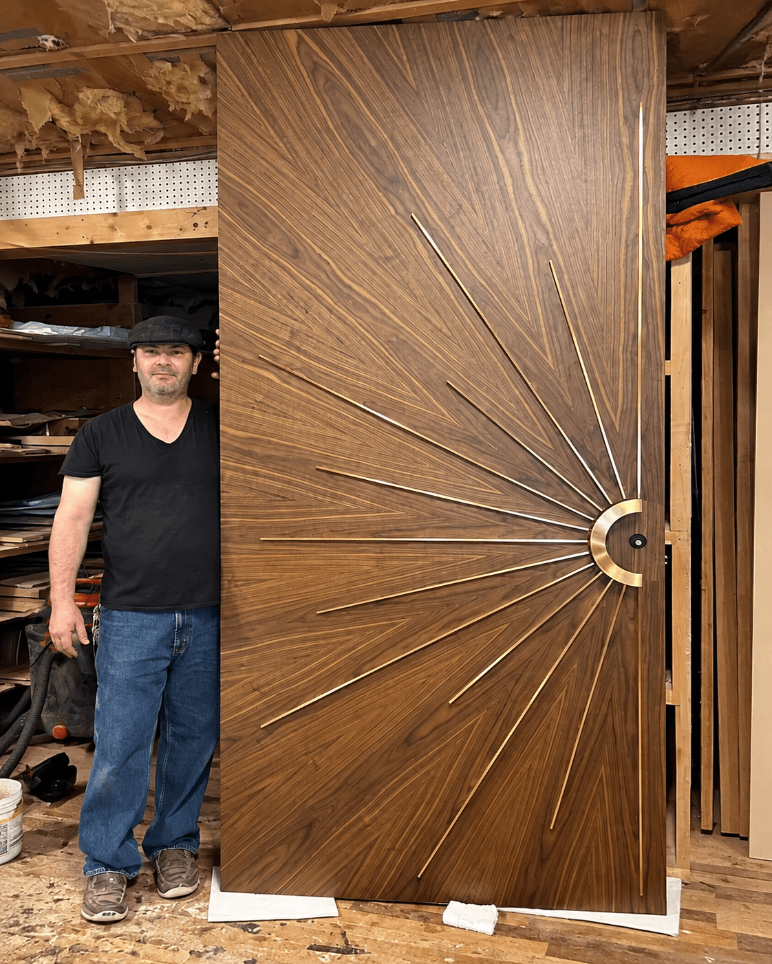 AURELIA designer wooden main door with a sunburst radial pattern, brass-tone inlays and circular handle detail, shown with a person for scale.