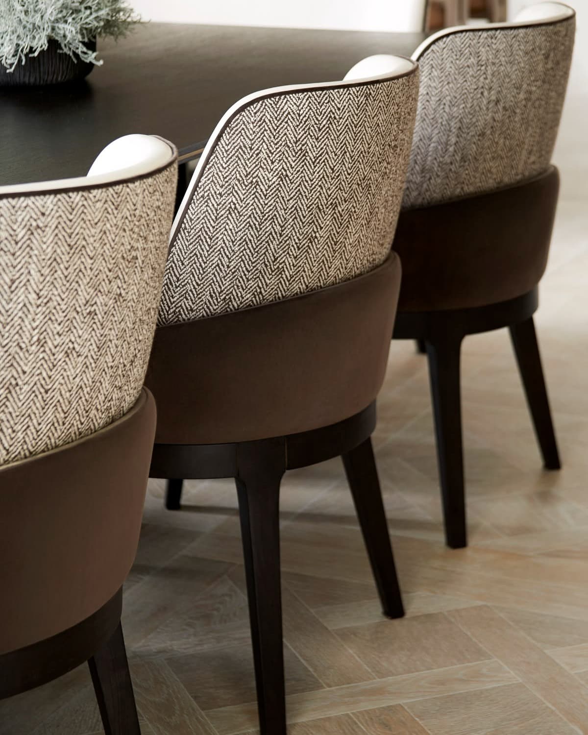 CÔTE premium dining chairs with curved upholstered backs, mocha lower upholstery and dark wooden legs arranged around a dining table.