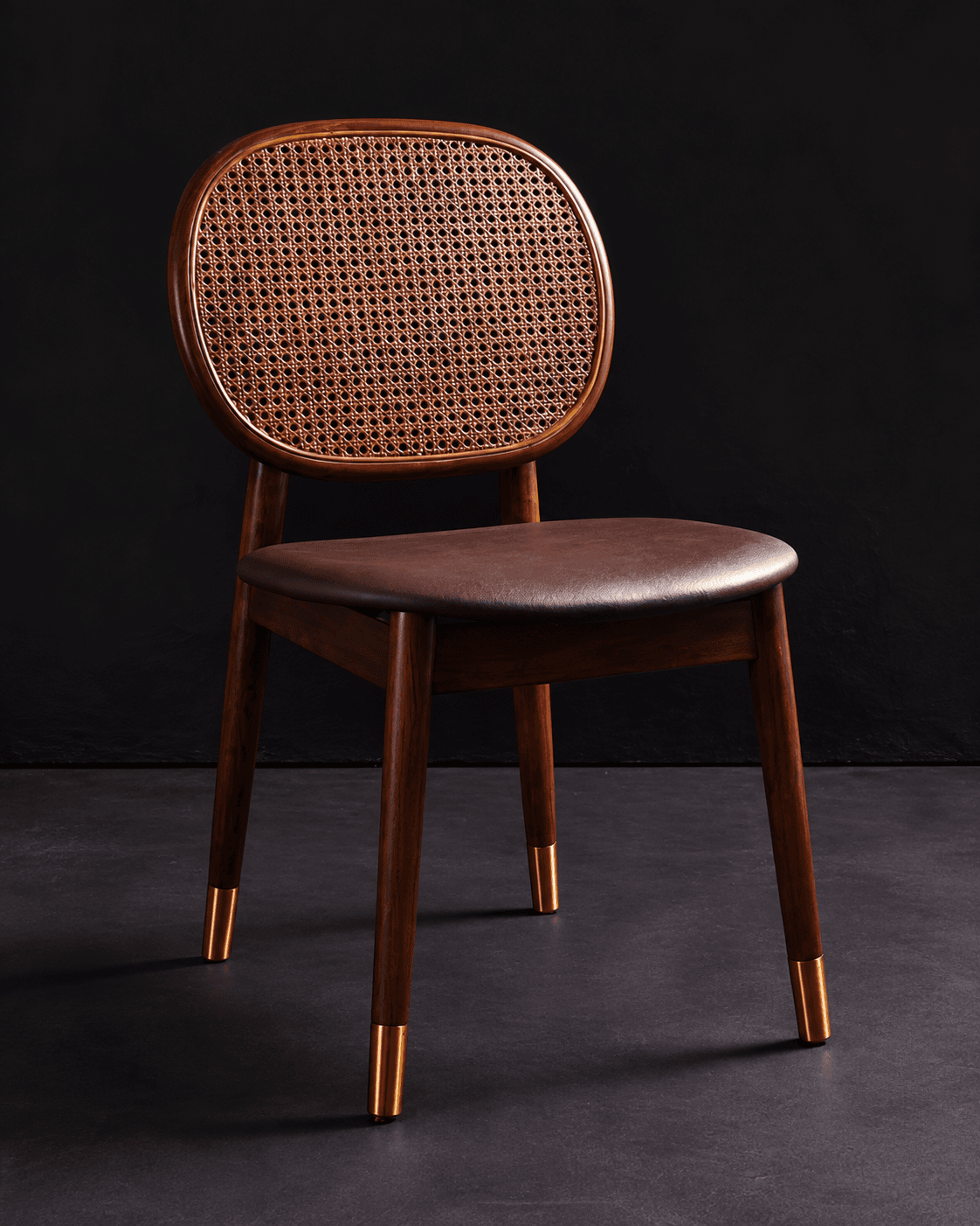 VIONA premium cane dining chair with a rounded cane backrest, upholstered seat, walnut frame and brass-gold foot caps in a dark interior.