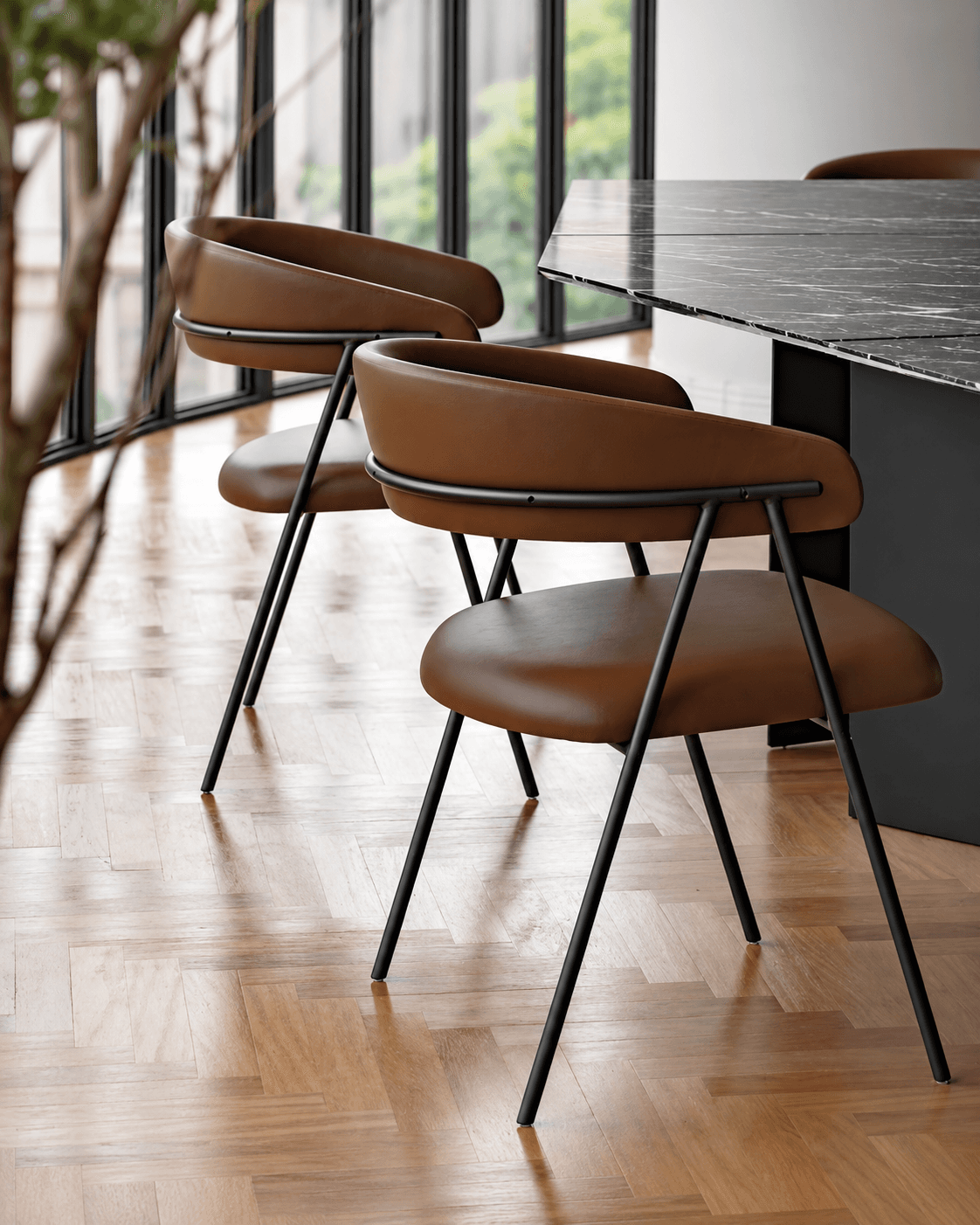 TALIA dining armchairs with curved brown upholstered seats and slim black metal frames in a contemporary dining setting.